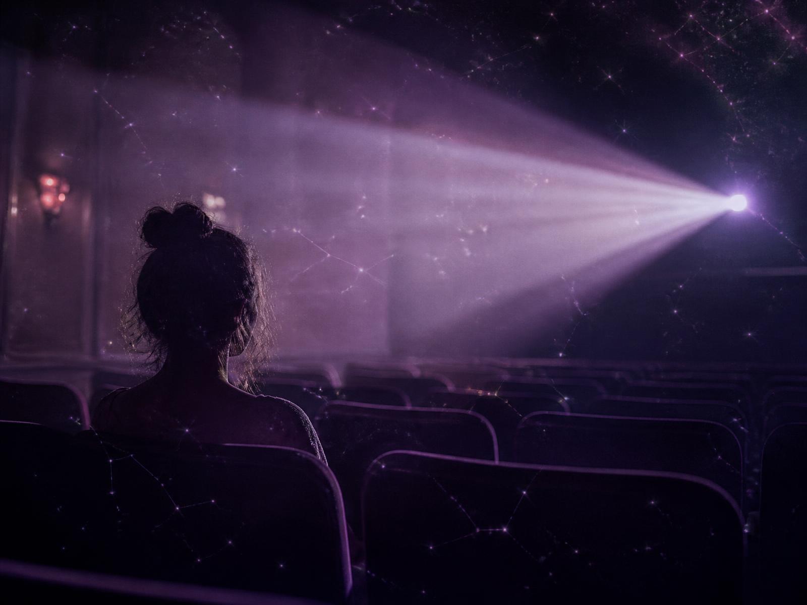Mulher sozinha em uma sala de cinema assistindo a uma cena, símbolo da constelação familiar em cenas